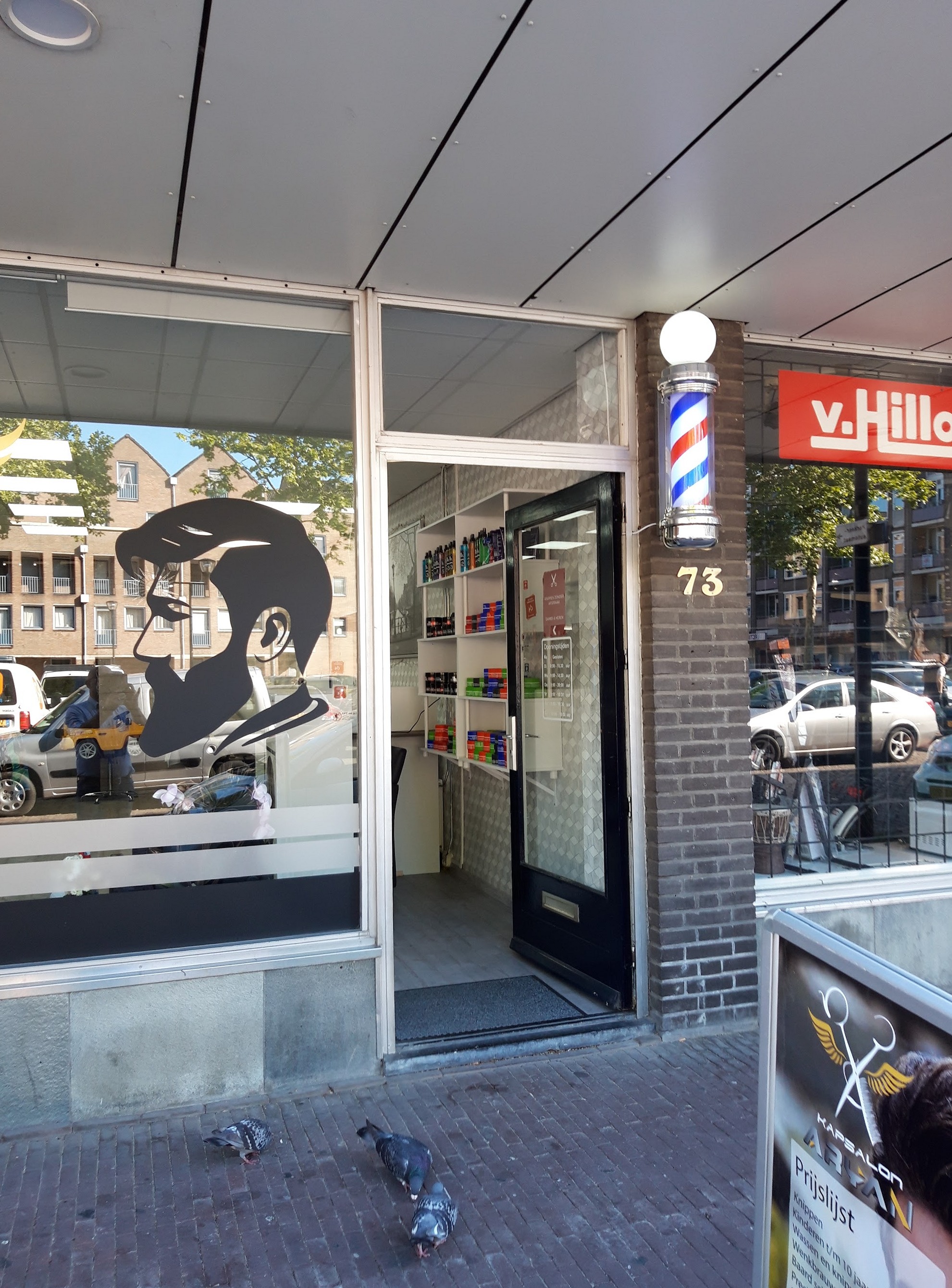 De deur van Kapsalon Aryan met huisnummer 73, de kapperspaal en de bebaarde man op het raam